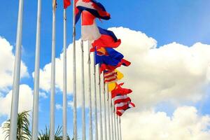 de nombreux drapeaux de l'asean aux couleurs colorées soufflés par la force du vent flottant sur un poteau devant un hôtel en thaïlande sur fond de nuages et de ciel bleu. photo