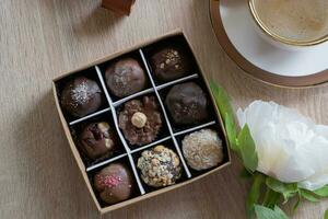 Chocolat artisanat des sucreries dans boîte avec café et fleur sur table Haut voir, plat allonger photo