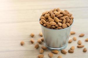 Amandes dans un seau en acier inoxydable sur table en bois avec espace de copie photo