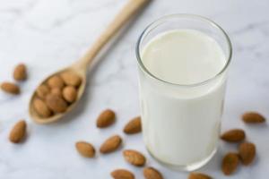 Amandes dans une cuillère en bois et lait d'amande sur marbre blanc photo