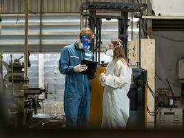 urgence la pollution usine concept. le ingénieur, portant une mécanicien combinaison et ppe et gaz masque, regards à le caméra avec le sien bras franchi. photo