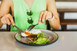 femme en mangeant petit déjeuner de poché des œufs sur pain grillé dans restaurant. photo