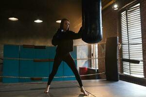 femmes soi la défense fille pouvoir. fort femme combattant formation poinçons sur boxe anneau. en bonne santé fort fille perforation boxe sac. formation journée dans boxe salle de sport. force en forme corps faire des exercices entraînement. photo