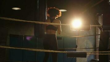 femmes soi la défense fille pouvoir. africain américain femme combattant formation poinçons sur boxe anneau. en bonne santé fort fille perforation boxe sac. formation journée dans boxe salle de sport. force en forme corps faire des exercices entraînement. photo