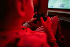 garçon joueur jouer manette de jeu Football vidéo Jeu console dans rouge jeu chambre. photo