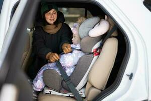 mère ceinture enfant sécurité siège chaise avec bébé fille est sur retour siège de auto. photo