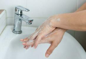 adultes laver leur mains avec main savon à prévenir infection et virus photo