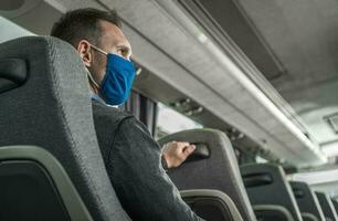 Hommes dans sécurité respiration masque sur le sien visage en voyageant seul dans une autobus entraîneur photo
