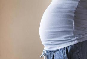 Une vue rapprochée du ventre d'une femme enceinte vue de côté sur un fond jaune