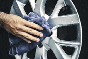 la main humaine essuie la roue en alliage de la voiture avec un chiffon en microfibre