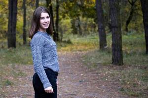 jolie fille dans un pull gris dans la forêt d'automne photo