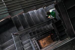 Un homme qui monte la cage d'escalier carrée en acier, vue du haut photo