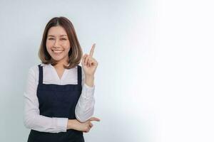 femme d'affaires asiatique pointant le doigt, montrant le numéro un et souriant. photo