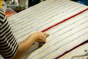 lampang, Thaïlande, 2018 - fermer main de gens utilisé montrer du doigt les doigts sélectionner Nombres à acheter thaïlandais loto sur loto planches dans le marché. photo