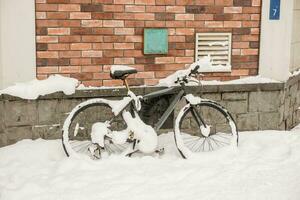 un vélo garé à à côté de bâtiment et couvert par neige de une lourd tempête de neige dans Otaru ville. photo