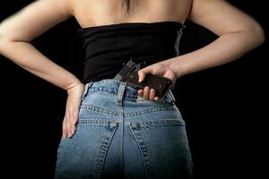 Femme avec un pistolet à la taille sur un fond noir photo