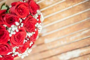 romantique rouge des roses dans une rustique Contexte. fleur arrangement de des roses sur minable en bois Contexte. salutation carte concept. mariage ou anniversaire artistique concept photo