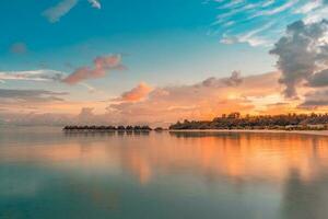 incroyable le coucher du soleil ciel et réflexion sur calme mer, Maldives plage paysage de luxe plus de l'eau bungalows. exotique paysage de été vacances vacances Contexte. magnifique horizon et parfait réflexion photo