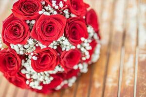 romantique rouge des roses dans une rustique Contexte. fleur arrangement de des roses sur minable en bois Contexte. salutation carte concept. mariage ou anniversaire artistique concept photo