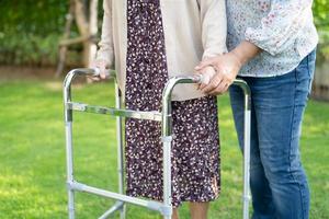 Aide et soins asiatique senior ou vieille dame âgée utiliser marcheur avec une bonne santé tout en marchant au parc en joyeuses vacances fraîches photo