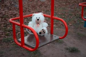 Gros plan d'un ours en peluche assis sur une balançoire pour enfants photo