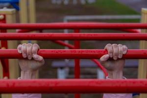 fille accrochée au bar à deux mains sur le parc extérieur photo