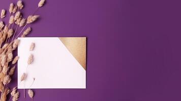 Haut vue de blanc et d'or Vide papier avec séché pampa herbe sur violet Contexte. mariage carte et espace pour votre message. génératif ai. photo