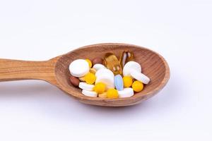 Médicaments et médicaments dans une cuillère en bois sur fond blanc avec espace de copie photo