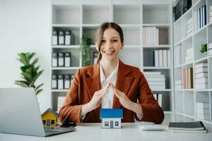 agent immobilier féminin utilise les mains pour protéger le toit rouge pour le concept d'investissement immobilier sur le commerce de la maison, achat au bureau au bureau photo
