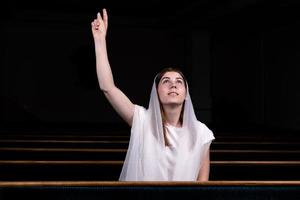 une jeune fille modeste avec un mouchoir sur la tête est assise à l'église et prie