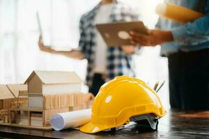 bureau d'ingénieur avec papier objet et tablette avec travail d'équipe d'ingénieurs flous travaillant dur pour consulter sur leur projet de construction. photo