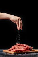 La main féminine saupoudre le sel sur le steak de boeuf