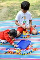 deux content garçons dans société parc, content asiatique frères qui sont souriant Heureusement ensemble. frères jouer en plein air dans été, meilleur amis. bambin bébé garçon en jouant avec le sien content frère dans le jardin photo