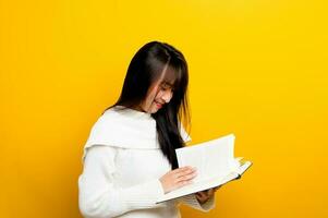 lis une livre, étude avec le protagoniste, chercher connaissance, nourriture pour pensée, fille en train de lire une livre et souriant. dans le photo studio Jaune toile de fond