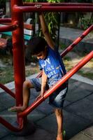 asiatique garçon Faire routine exercice dans société parc pendant le Matin temps. mignonne peu enfant exercice et Gym à garder lui-même en forme pour vie. enfant exercice Extérieur tirer photo