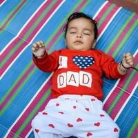 mignonne peu Indien bébé séance profiter Extérieur tirer à société parc dans Delhi, mignonne bébé garçon séance sur coloré tapis avec herbe autour, bébé garçon Extérieur tirer photo