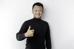 excité asiatique homme portant noir chemise donne les pouces en haut main geste de approbation, isolé par blanc Contexte photo