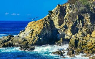 surfeur vagues turquoise bleu l'eau rochers falaises rochers puerto escondido. photo