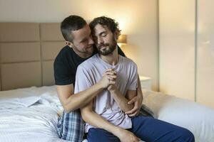 gay couple embrassement chaque autre avec leur yeux fermé. deux Jeune Masculin les amoureux émouvant leur visages ensemble tandis que dans lit dans le Matin. affectueux Jeune gay couple collage à maison. photo