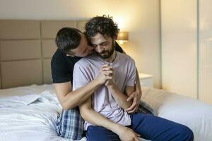 gay couple embrassement chaque autre avec leur yeux fermé. deux Jeune Masculin les amoureux émouvant leur visages ensemble tandis que dans lit dans le Matin. affectueux Jeune gay couple collage à maison. photo