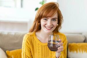 femme en portant verre en buvant Naturel l'eau. assez de quantité aqua améliore peau complexion, augmente énergie, la prévention de corps déshydratation, en bonne santé mode de vie concept photo