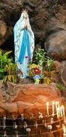 statue de saint vierge Marie dans romain catholique église, dans le la grotte de vierge Marie, dans une Roche la grotte chapelle catholique église avec tropical fleurs autour photo