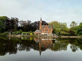 eau minérale ancien médiéval gothique rouge brique Château à le Lac de l'amour dans Bruges dans Publique parc zone, Belgique, brillant ensoleillé jour, magnifique Naturel paysage, bâtiment réflexion dans l'eau photo