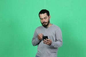 asiatique homme expression tandis que en utilisant téléphone intelligent photo