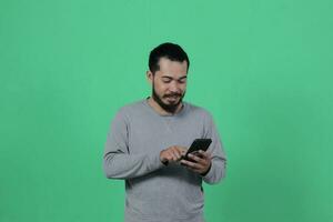 asiatique homme expression tandis que en utilisant téléphone intelligent photo