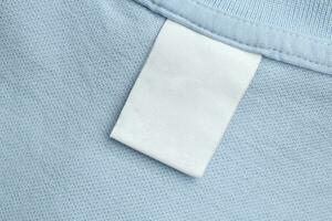 étiquette blanche de vêtements de soin de blanchisserie vierge sur fond de tissu de chemise bleue photo