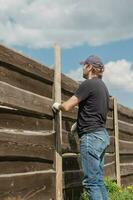 un adulte homme est engagé dans charpenterie travail à une maison construction site - une en bois clôture et terrasse planches photo