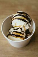 des balles de crémeux la glace crème dans une papier carton tasse avec Chocolat caramel Garniture photo