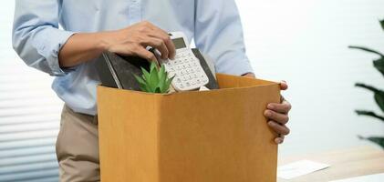 affaires homme Envoi en cours démission lettre et emballage des trucs démissionner déprimer ou porter affaires papier carton boîte par bureau dans bureau. changement de emploi ou mis à la porte de entreprise photo