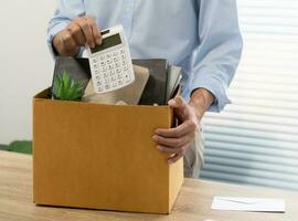 affaires homme Envoi en cours démission lettre et emballage des trucs démissionner déprimer ou porter affaires papier carton boîte par bureau dans bureau. changement de emploi ou mis à la porte de entreprise photo